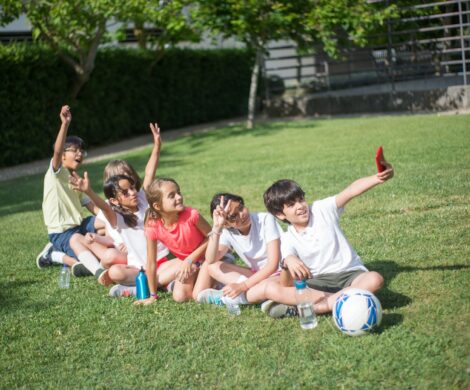 Grupo de niños disfrutando de un día soleado, tomando un divertido selfie en la hierba.