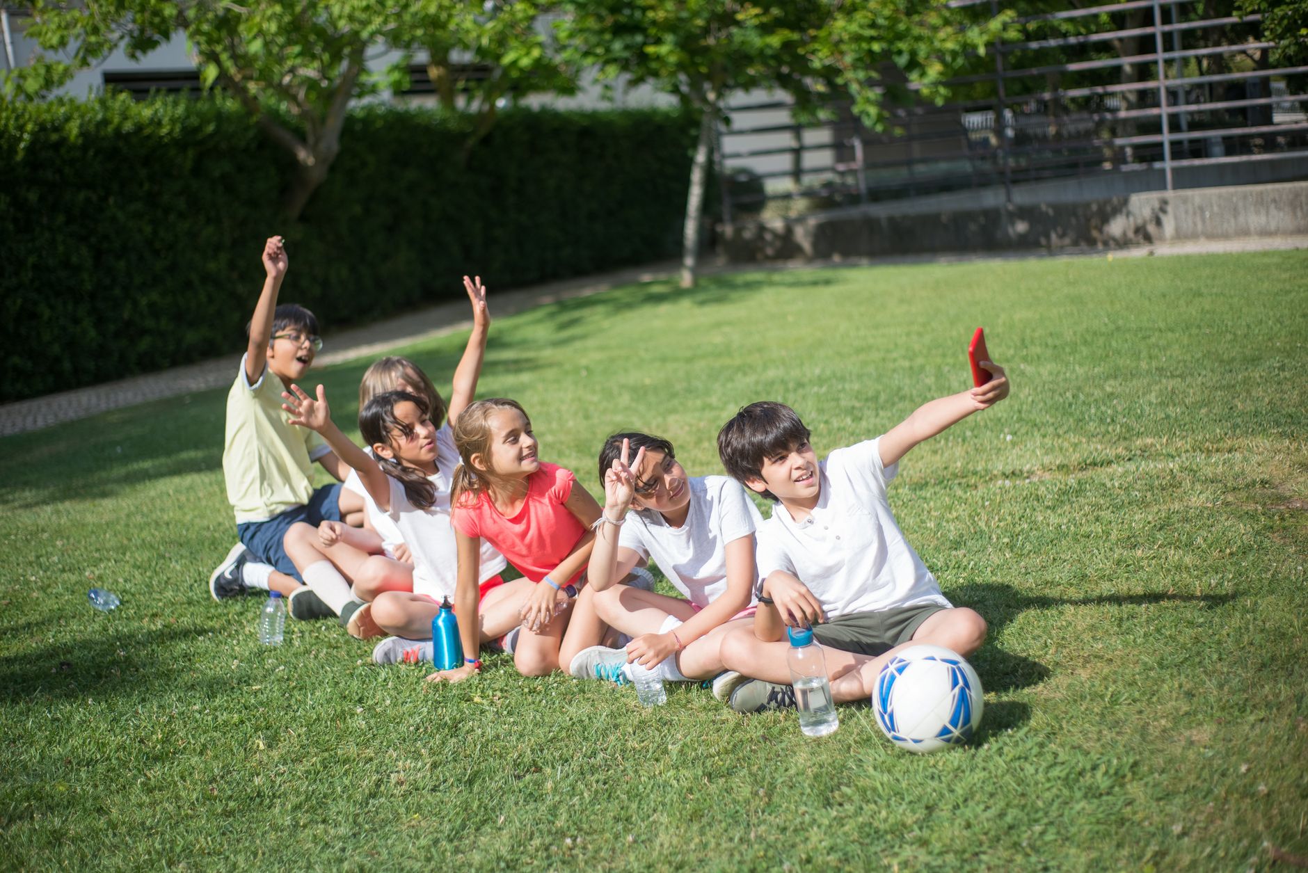 Grupo de niños disfrutando de un día soleado, tomando un divertido selfie en la hierba.